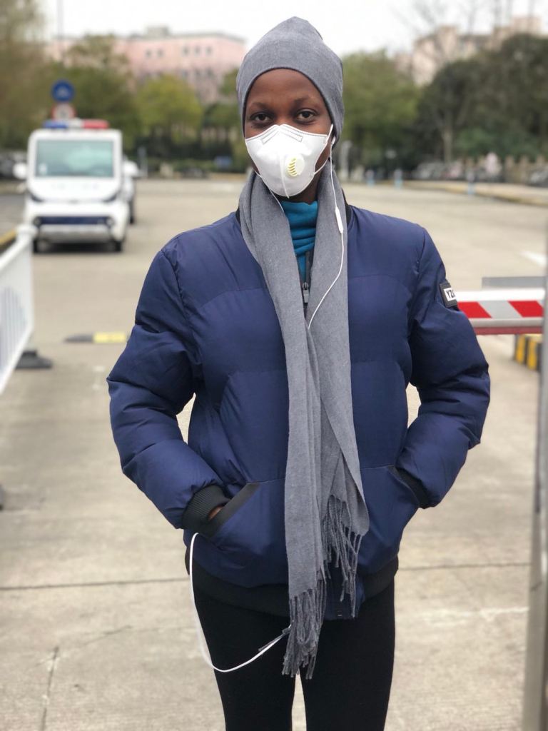 Augustina standing with mask on face and wearing coat